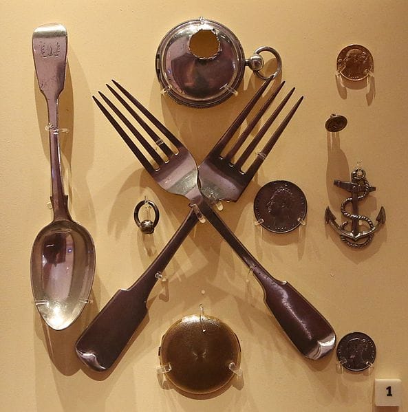 Some Franklin relics: forks, spoons, coins. Two of the forks are crossed (maybe a bit ominously?)